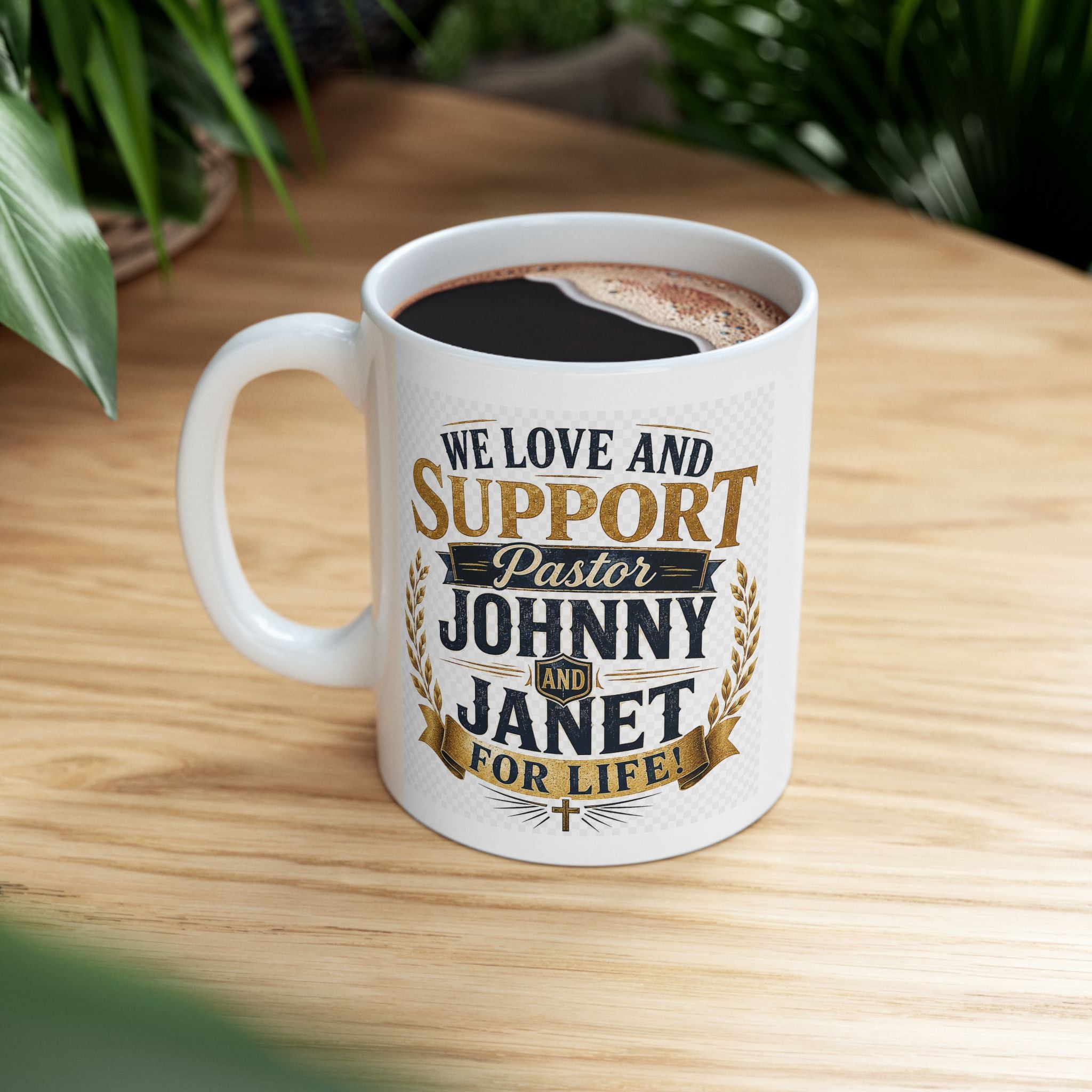 White mug with text and coffee on a wooden table We Love and Support Johnny and Janet for Life 